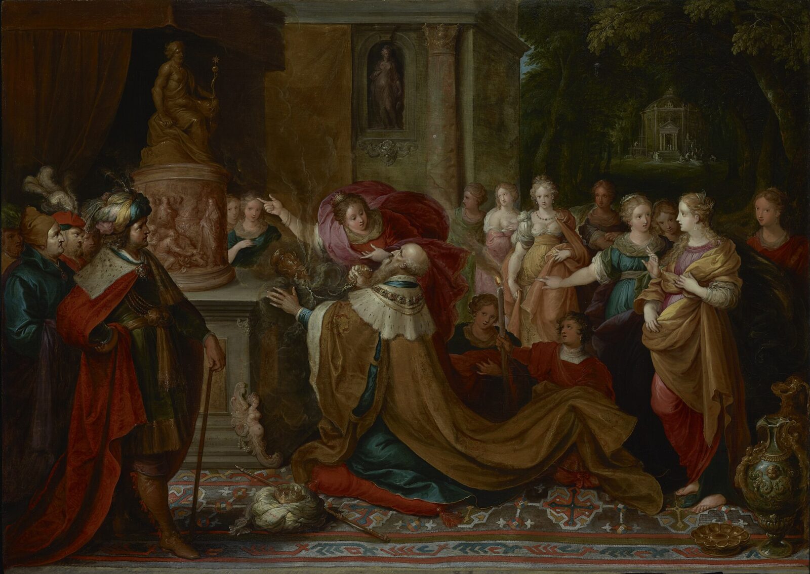 King Solomon kneels before a pagan idol at an altar, urged on by his foreign wives.