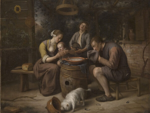 A Dutch family bows their heads in prayer around a table before a meal.