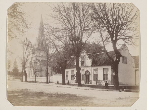 An old photograph of a street in Stellenbosch with a house and a church.