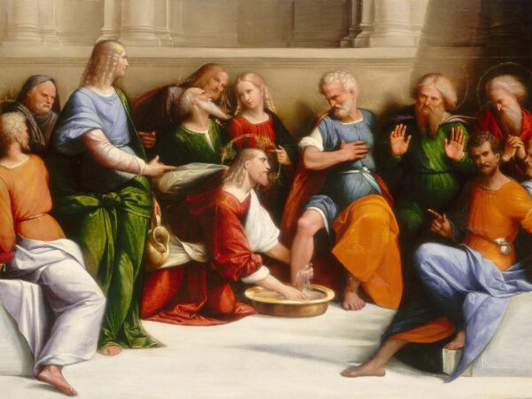 Christ kneels before Peter to wash his feet while the other disciples look on.