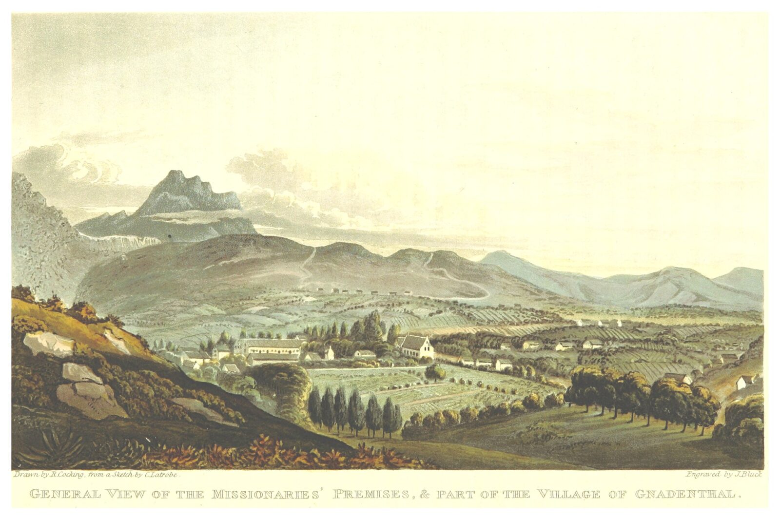 A mission church and village spread across a valley below mountains in the Cape.