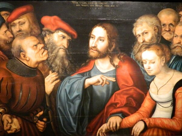 Christ takes the hand of a woman brought before him while a crowd of accusers presses close.