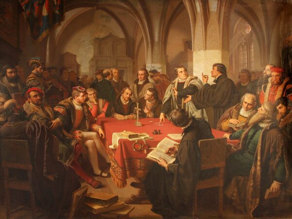 Luther, Zwingli and other Reformers debate across a table at Marburg Castle in 1529.