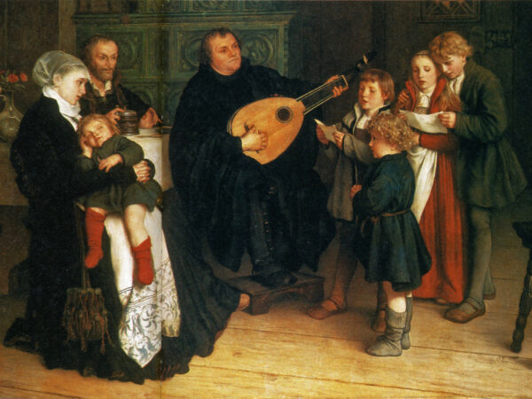 Martin Luther plays the lute at home while his wife, children and friends sing around him by lamplight.