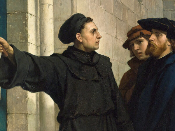 Martin Luther fixes his Ninety-Five Theses to the church door in Wittenberg while townspeople look on.